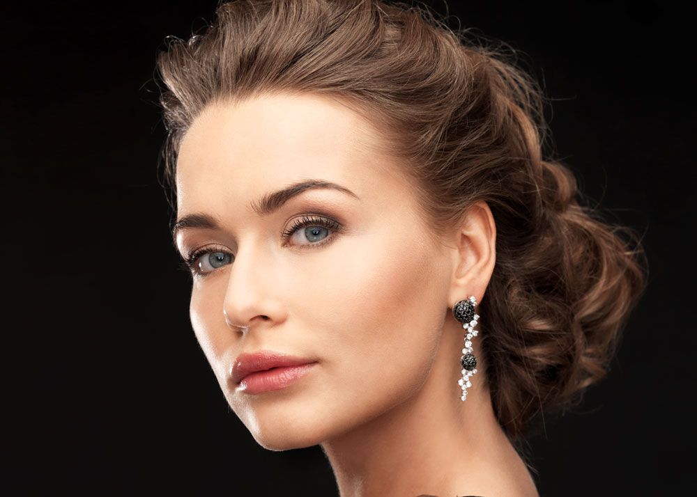 Woman wearing elaborate diamond drop earrings and looking directly into the camera