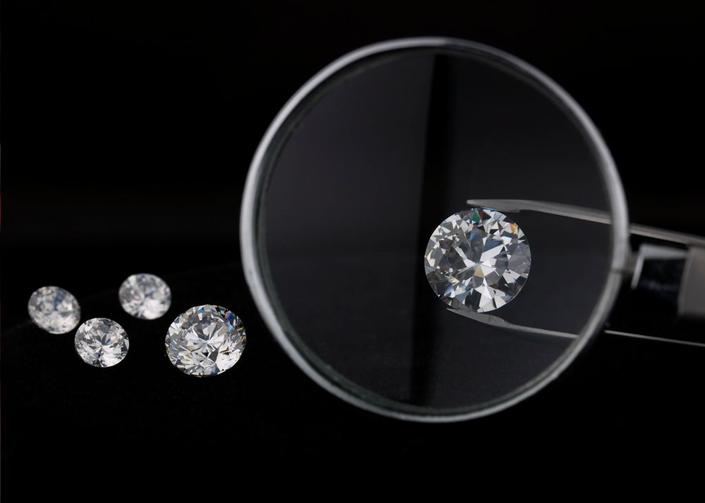 Magnifying glass over diamond, near other diamonds.